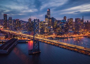 A photo of San Francisco at night with the San Francisco Bridge in the foreground.