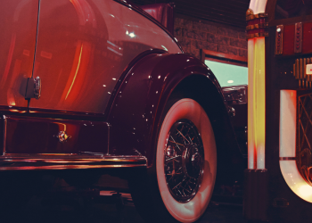 An old-time car in front of a old-time jukebox.