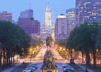 A photo of downtown Philadelphia looking down a main thoroughfare with trees on the side and the capitol in the distance.