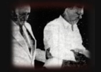 A picture of Bobby Ross being led out of a courthouse by a federal agent.