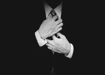 A picture of a faceless mobster fixing his tie.