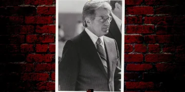 A photo of mobster tony plata dressed in a suit set on a signature button guys background.