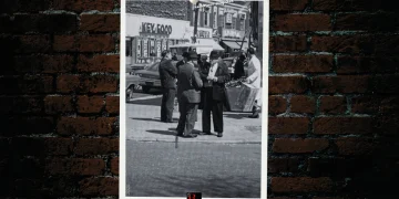 A photo of several men with fedoras talking on a street in Queens, NY